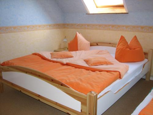 Bett mit orangefarbener und weißer Bettwäsche und Kissen in der Unterkunft Hotel-Pension Lydia in Berlin