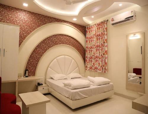 a bedroom with a large bed and a wall with a painting at Hotel Gopal, Khargone in Khargon