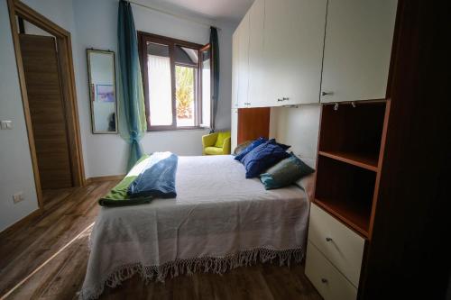 Un dormitorio con una cama con almohadas azules y una ventana en Affittacamere Oasi di Padru B&B en Magomadas