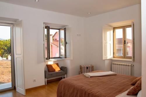 una camera da letto con un letto, una sedia e finestre di Beautiful cozy cottage near Nazaré, Leiria&Batalha a Juncal