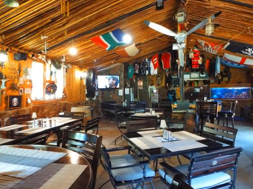 a restaurant with wooden tables and chairs and a tv at Aloes Country Inn in Waterval Boven