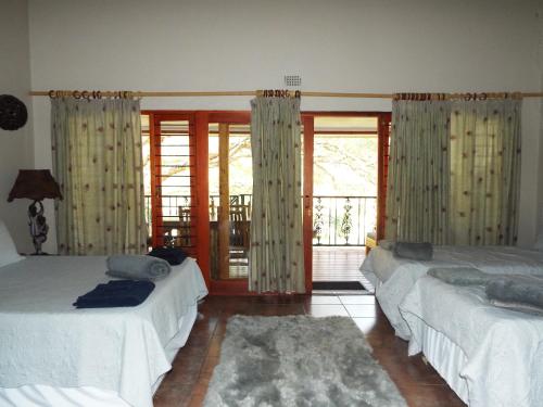 a bedroom with two beds and a balcony at Aloes Country Inn in Waterval Boven