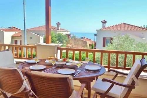 a wooden table and chairs on a balcony with the ocean at Belvedere, LaVanta, Kalkan in Kalkan