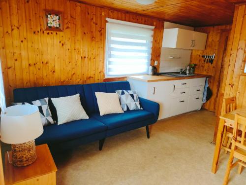 ein Wohnzimmer mit einem blauen Sofa und einer Küche in der Unterkunft Chata Slapy - Ždáň in Slapy nad Vltavou