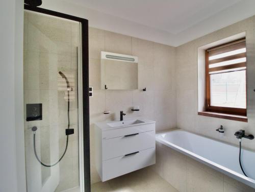 a bathroom with a tub and a sink and a shower at Apartmán uprostřed trojúhelníku Praha - Karlovy Vary - Plzeň in Kolešovice