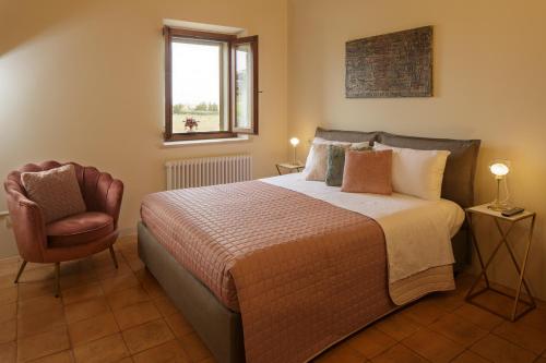 a bedroom with a bed and a chair and a window at SeiPetali in Cannara