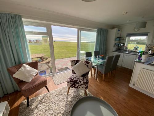 a living room with a table and chairs and a kitchen at BAYVIEW self-catering coastal bungalow in rural West Wight in Freshwater