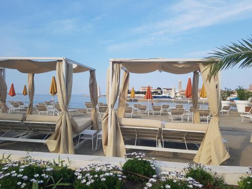a beach with chairs and umbrellas and the ocean at Apartment Lavanda garden in Rab