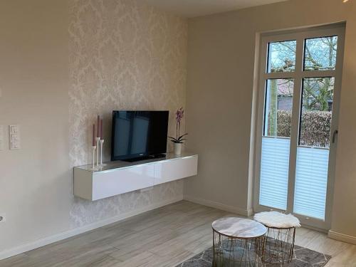 a living room with a tv and two stools at Schöne Ferienwohnung im Ergeschoss mit Terrasse in Ahaus