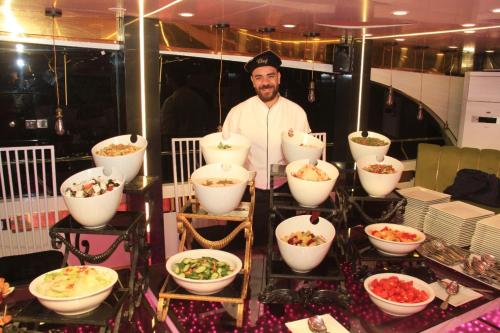 um homem parado em frente a uma mesa com tigelas de comida em نادى يخت الجيزة no Cairo