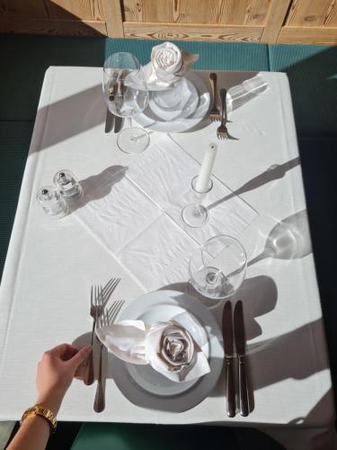 a table with white plates and silverware on it at Natur Pur Hotel Unterpichl in Ultimo