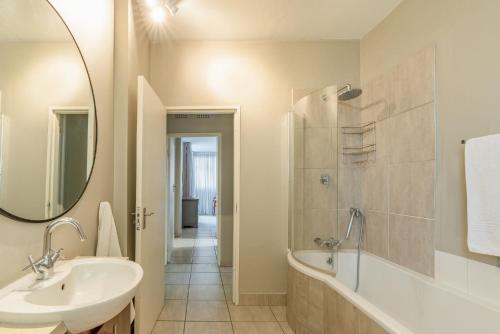 a bathroom with a sink and a tub and a mirror at Lovely 3 Bedroom apartment in the heart of Sandton 505 in Johannesburg