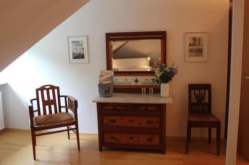 um quarto com uma cómoda com um espelho e 2 cadeiras em Wohnung mit Dachterrasse in Starnberg em Starnberg
