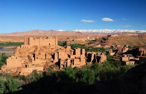 Un groupe de bâtiments en adobe dans le désert avec des montagnes en arrière-plan dans l'établissement Kasbah Tinariwin, à Taziricht