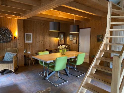 a dining room with a wooden table and green chairs at 't Wettenshuys in Nuenen