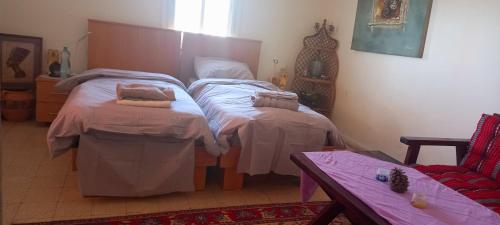 a bedroom with two twin beds and a table at Lazarus Guest House in Abū Dīs