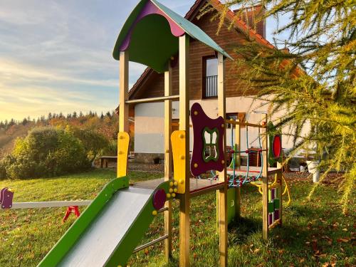 a playground with a slide in front of a house at Zagroda na Pacanach in Iwkowa