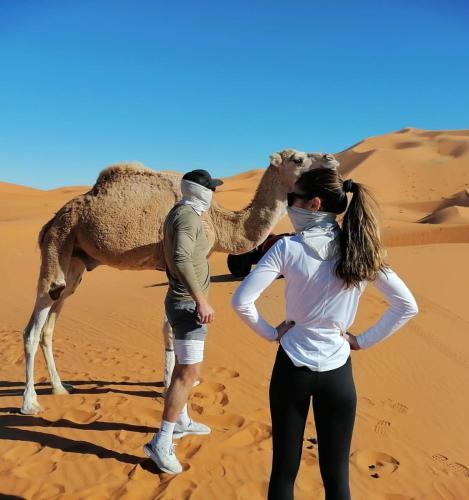 een man en een vrouw in de woestijn met een kameel bij top luxury desert camp in Erfoud