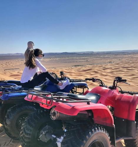 two people sitting on atvs in the desert at top luxury desert camp in Erfoud