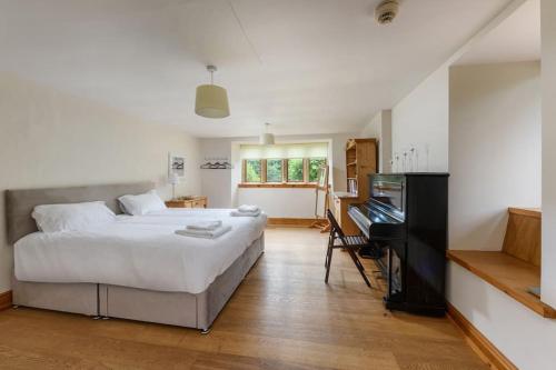 1 dormitorio con 1 cama blanca grande y piano en 10 Bed Stunning House in village, with Hot Tub, en Ovingham