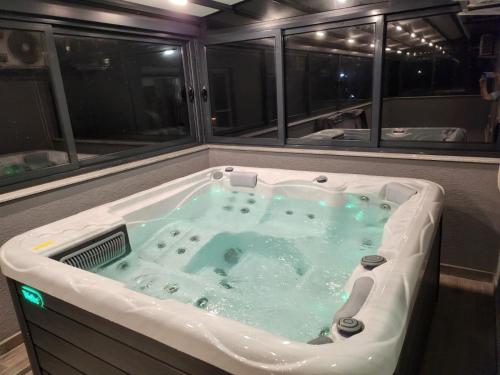 a jacuzzi tub in a room with windows at LUXURY VILLA M NEAR 2km AWAY FROM BITOLA WITH PRIVATE SWIMMING POOL & SAUNA &JACUZZI in Bitola