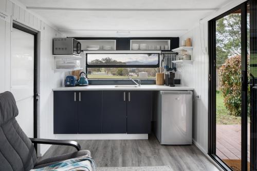 una cocina con armarios negros y un fregadero en una caravana en The Village Green Glampervans, en Strath Creek