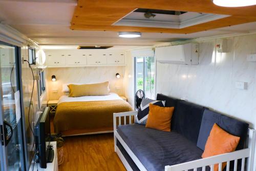 une caravane avec un lit et un canapé dans une chambre dans l'établissement The Village Green Glampervans, à Strath Creek