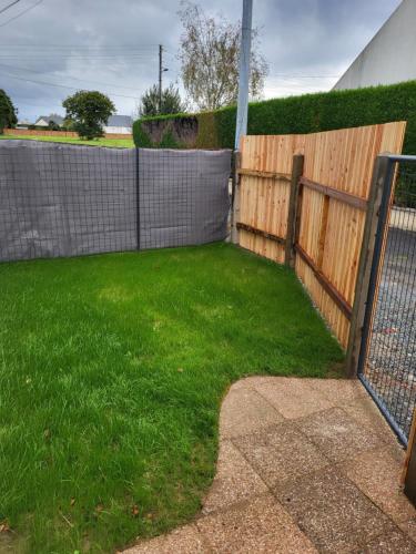 une clôture dans une cour avec de l'herbe verte dans l'établissement Le clos de la baie, à Cancale