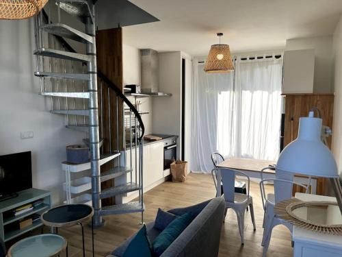 a living room with a table and a spiral staircase at LA CABINE VUE MER in Luc-sur-Mer