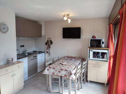 a kitchen with a table with chairs and a kitchen with a tv at Coquet Studio de 4 personnes aux Carroz - Balcon et Wifi in Les Carroz d'Araches