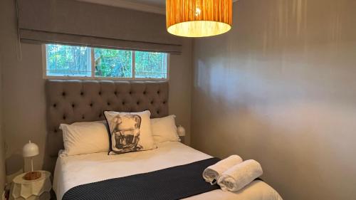 a bedroom with a bed with a headboard and a window at 35 on Fairview in Kloof
