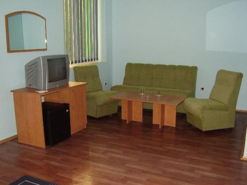 ein Wohnzimmer mit einem TV, einem Tisch und Stühlen in der Unterkunft Prima Hotel in Kharmanli