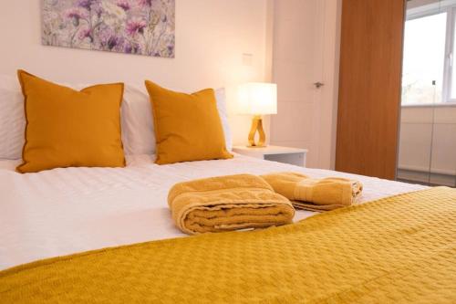 a bed with yellow pillows and towels on it at Panorama House, Modern 3-Bedroom Apartment 3, Oxford in Kidlington
