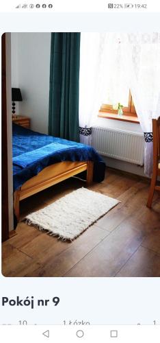 a bedroom with a blue bed and a window at DOM WESELNY 'DWÓR W JUROWCACH' in Sanok