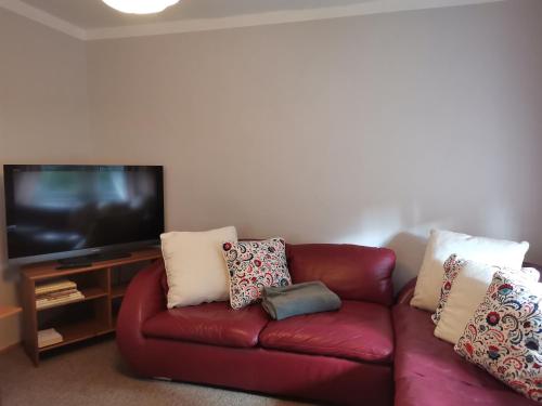 a living room with a red leather couch and a flat screen tv at Auszeit in Freital