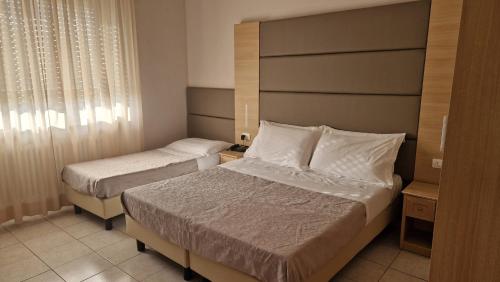 a hotel room with two beds and a window at Hotel Trasimeno Bittarelli in Castiglione del Lago