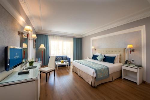 a hotel room with a large bed and a television at Premier Le Reve Hotel & Spa Sahl Hasheesh - Adults Only 16 Years Plus in Hurghada