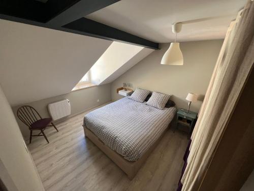 een slaapkamer met een bed en een stoel op zolder bij Appartement grand standing plein centre ville in Cauterets