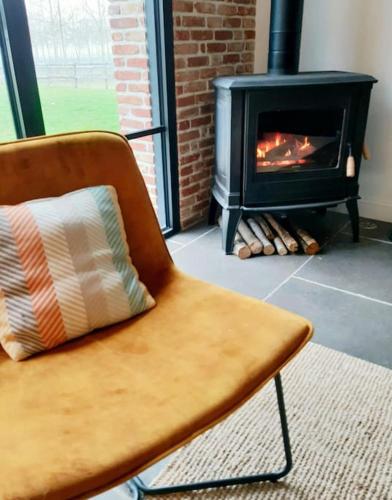 une chaise avec un oreiller en face d'une cheminée dans l'établissement Gite Le Clos Sainton, à Saint-Hilaire-Saint-Mesmin