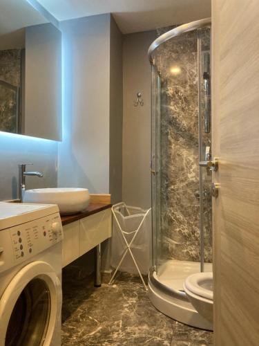 a bathroom with a shower and a sink and a washing machine at Aryan Suit. in Istanbul