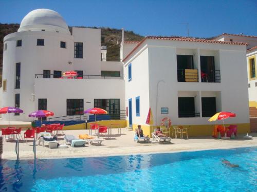 una piscina frente a un edificio con sombrillas en HI Alcoutim – Pousada de Juventude, en Alcoutim