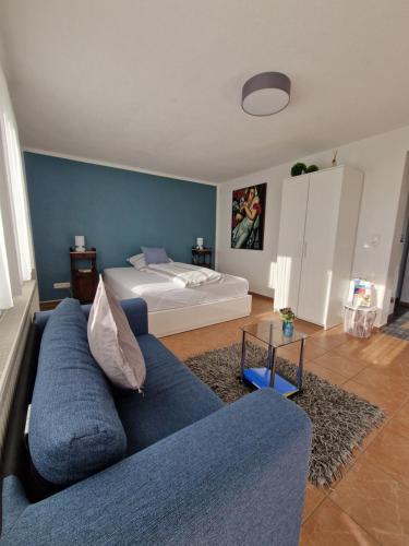 a living room with a blue couch and a bed at Ferienwohnung am sonnigen Haimberg in Fulda
