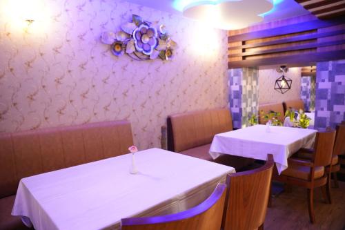 two tables in a restaurant with white table cloth at Hotel EDEN in Kārwār