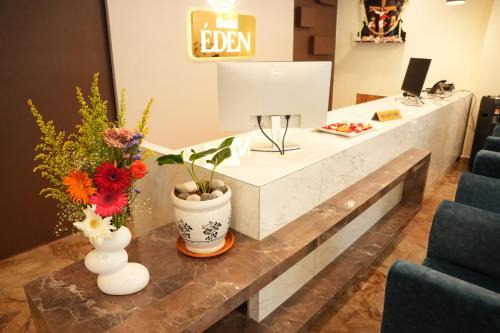 a reception desk with flowers in vases on a table at Hotel EDEN in Kārwār