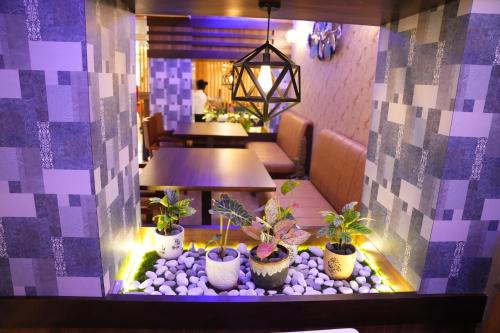 a restaurant with potted plants in a room with purple lighting at Hotel EDEN in Kārwār
