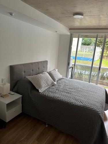 a bedroom with a bed and a large window at Apartamento a estrenar en complejo Mansa inn2 in Punta del Este