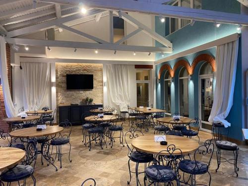 a dining room with tables and chairs and a flat screen tv at Pensiunea ALLEGRIA in Baile Unu Mai