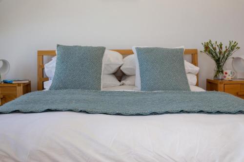 a bed with two blue pillows on top of it at St Helen’s House in Padstow