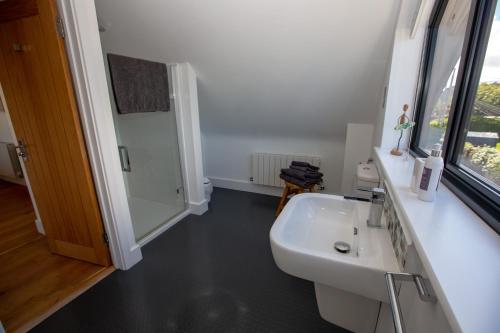 a white bathroom with a sink and a window at St Helen’s House in Padstow