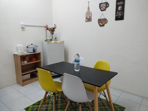 uma mesa de jantar com 4 cadeiras e um frigorífico em WAFID HOMESTAY SERI ISKANDAR em Seri Iskandar